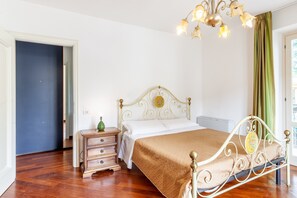 Une chambre à coucher avec un lit, une table de chevet, une commode, un lustre et une porte.
