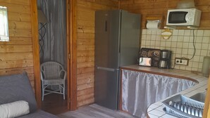 Un interior acogedor de cabaña con sofá, refrigerador, microondas y pileta.