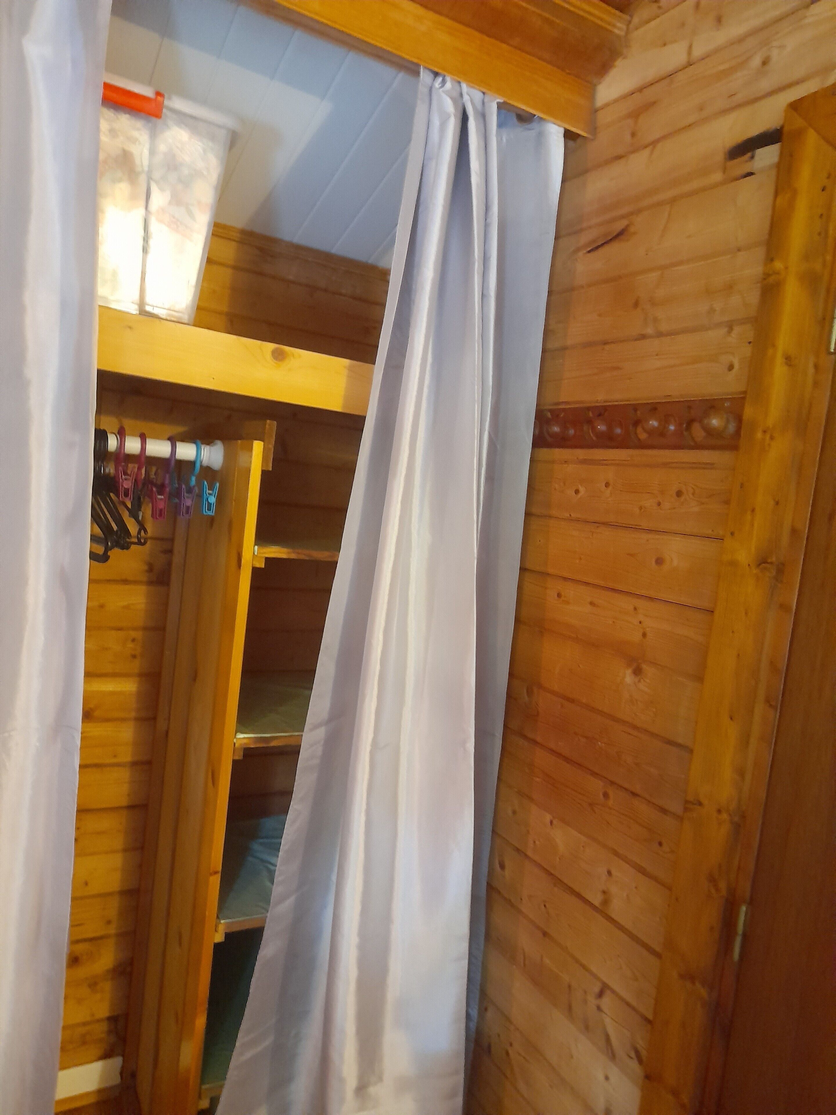 A wooden interior with a shelf and hanging items.