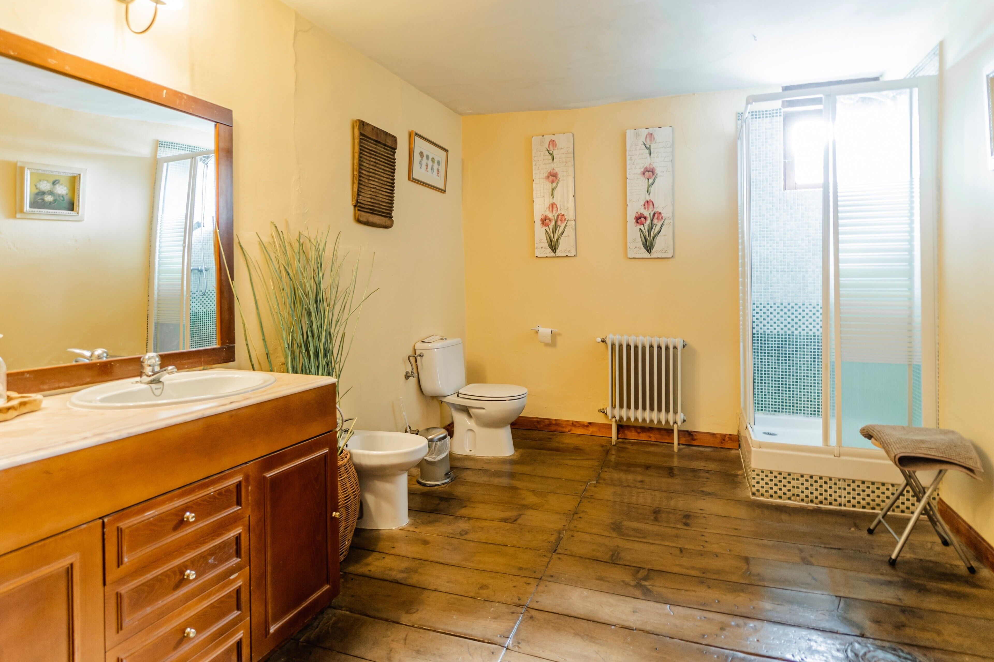 A bathroom with a wooden vanity, a toilet, a bidet, and a radiator.
