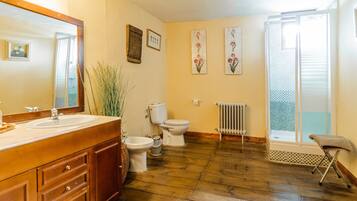 A bathroom with a wooden vanity, a toilet, a bidet, and a radiator.