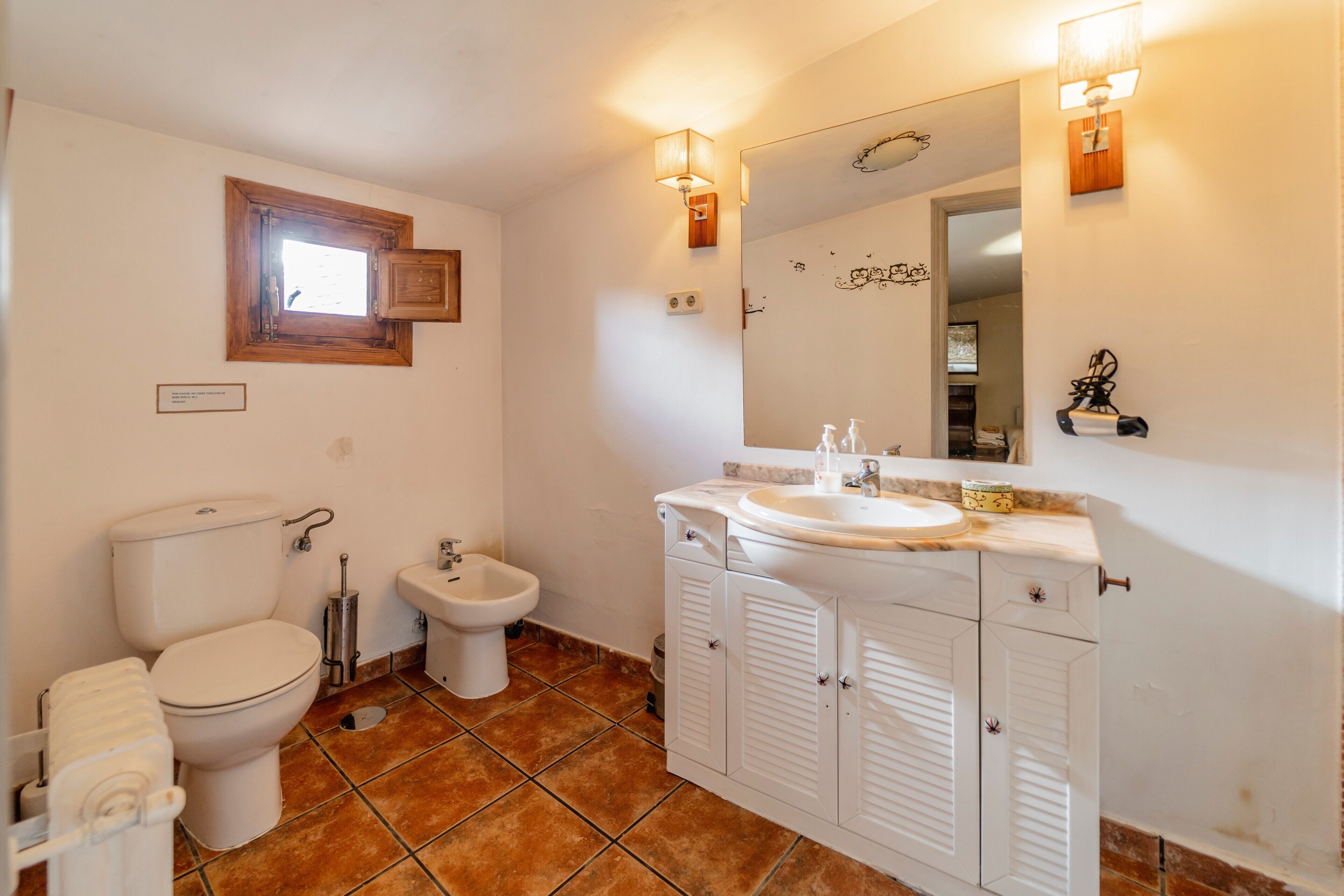 Une salle de bain équipée de toilettes, d’un bidet, d’un lavabo et d’un miroir.