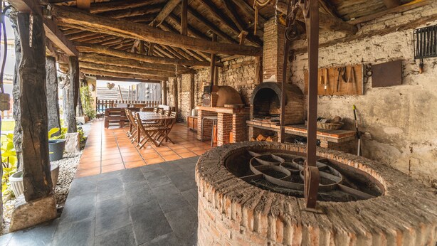 A rustic interior with exposed brick walls, a stone fireplace, wooden beams, and a tiled floor. - Casa Rural 'Laguna Herrera' in Segovia – Private Pool, Garden, Sleeps up to 14 (Campo de Cuéllar)
