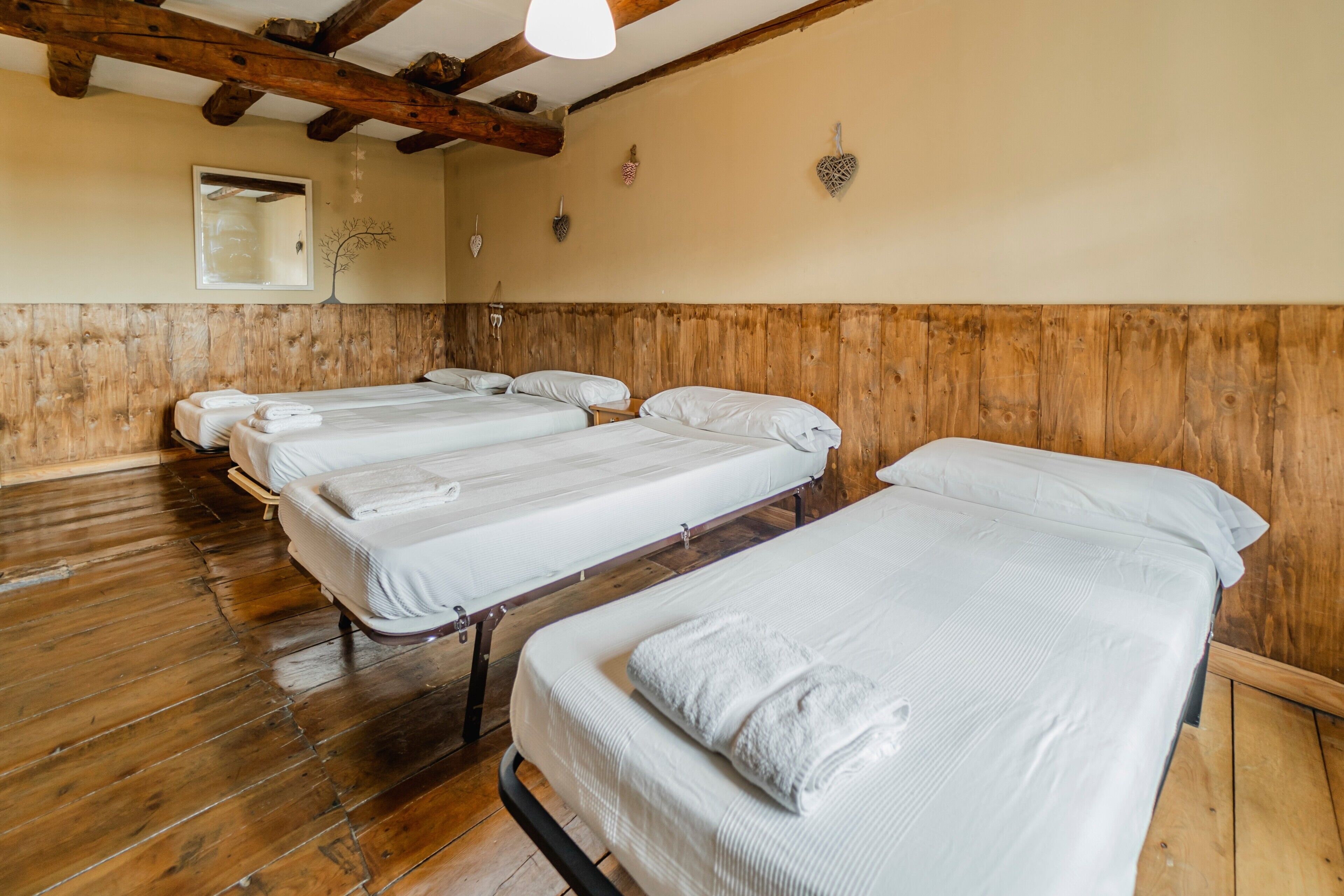 Une pièce avec un plancher en bois, un plafond en bois et un lit recouvert de linge de lit blanc.