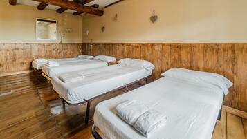 Une pièce avec un plancher en bois, un plafond en bois et un lit recouvert de linge de lit blanc.