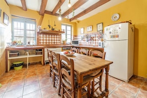 Una cocina con mesa y sillas de madera, un refrigerador y una ventana con vistas.
