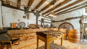 A rustic room with a foosball table, wooden barrels, and a stone wall. - Casa Rural 'Laguna Herrera' in Segovia – Private Pool, Garden, Sleeps up to 14 (Campo de Cuéllar)