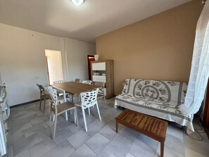 A living room with a sofa, a wooden coffee table, a dining table with chairs, and a cabinet.