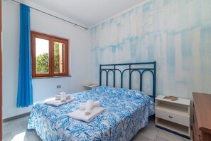 Ein Schlafzimmer mit Bett, Fenster, Nachttisch und Kommode.