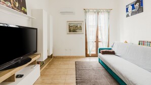 A living room with a flat-screen TV, a sofa, a rug, and artwork on the walls. - Apartment 'Casa Rimedia' with Balcony, Wi-Fi and Air Conditioning (Solanas)