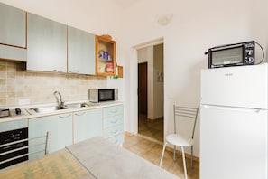 A kitchen with light blue cabinets, a microwave, a toaster, and a white refrigerator. - Apartment 'Casa Rimedia' with Balcony, Wi-Fi and Air Conditioning (Solanas)