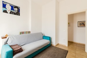 A living room with a teal sofa, a patterned rug, and a painting on the wall. - Apartment 'Casa Rimedia' with Balcony, Wi-Fi and Air Conditioning (Solanas)