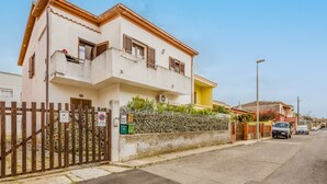 A two-story residential building with a gated entrance, a balcony, and a small garden area. - Apartment 'Casa Rimedia' with Balcony, Wi-Fi and Air Conditioning (Solanas)