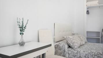 Een slaapkamer met een bed, een nachtkastje, een stoel, een kledingkast en een vaas met een plant.
