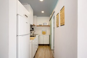 A narrow kitchen with white cabinets, a microwave, and a wooden countertop.