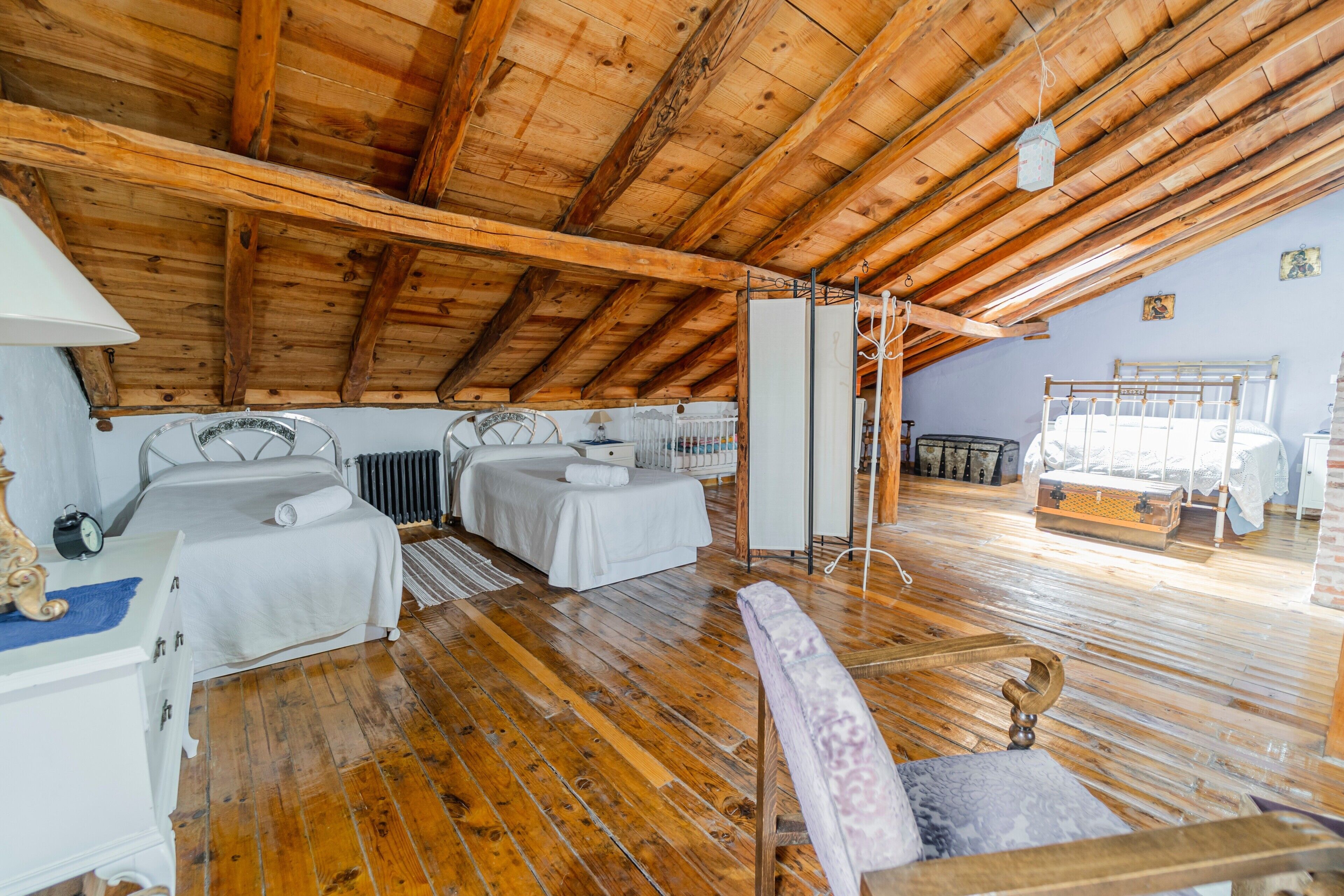 Ein Schlafzimmer im Dachgeschoss mit Holzboden, zwei Betten, einer Heizung und einer Holzaussparung an der Decke.
