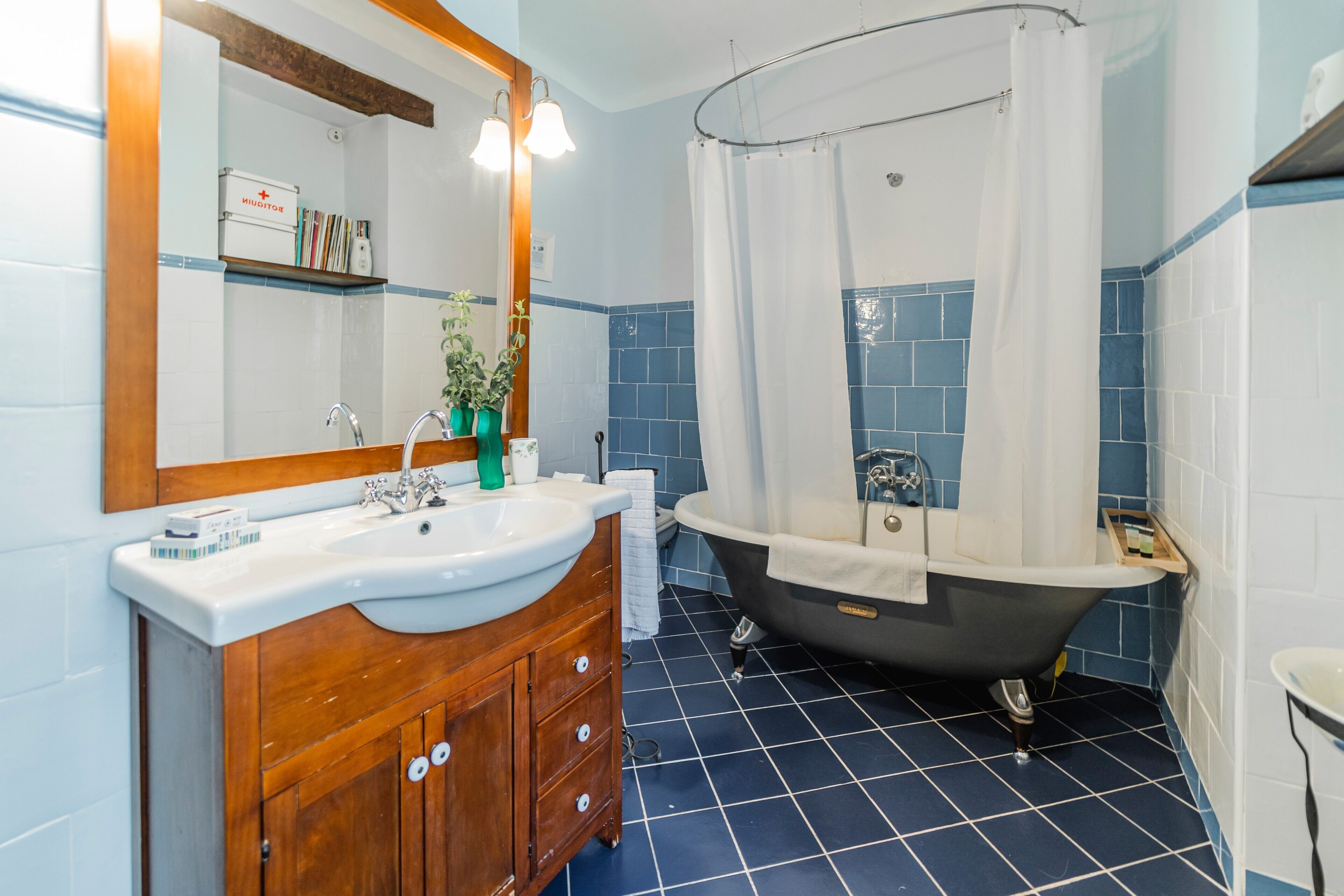 Un baño con tocador de madera, un lavabo blanco, una bañera y una cortina de ducha.