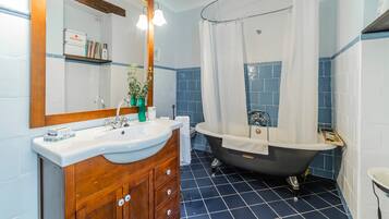 Un baño con tocador de madera, un lavabo blanco, una bañera y una cortina de ducha.