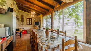 Una cucina rustica con un tavolo da pranzo, sedie di legno, un'ampia finestra vista e pareti in pietra.