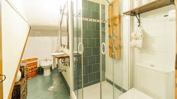 A bathroom with a glass-enclosed shower, a toilet, and a sink.