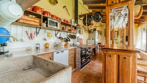 Una cucina con lavello in pietra, mobili in legno e diversi utensili da cucina.