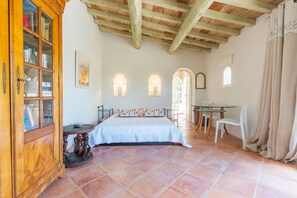 A bedroom with a bed, a wooden cabinet, a round table, and a chair.