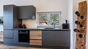 A modern kitchen with a built-in oven, a coffee machine, and a large window. - Apartment 'Penthouse -  Venosta' with Mountain View, Balcony and Wi-Fi (Naturno)