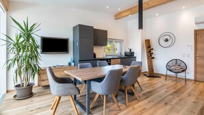 A modern kitchen with a dining area, wooden floors, and a large potted plant. - Apartment 'Penthouse -  Venosta' with Mountain View, Balcony and Wi-Fi (Naturno)