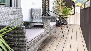 A balcony with wicker furniture, a glass table, and a potted plant. - Apartment 'Penthouse -  Venosta' with Mountain View, Balcony and Wi-Fi (Naturno)