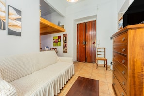 Un salón acogedor con sofá, cómoda de madera y una puerta que da a otra habitación.