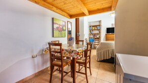 A dining area with wooden chairs and a table, a kitchen with a refrigerator, and a bookshelf. - Apartment 'Casa Musio' (Cagliari)