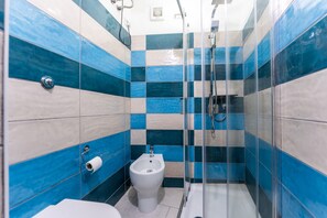A bathroom with a bidet, toilet paper, and a shower enclosure. - Apartment 'Casa Musio' (Cagliari)