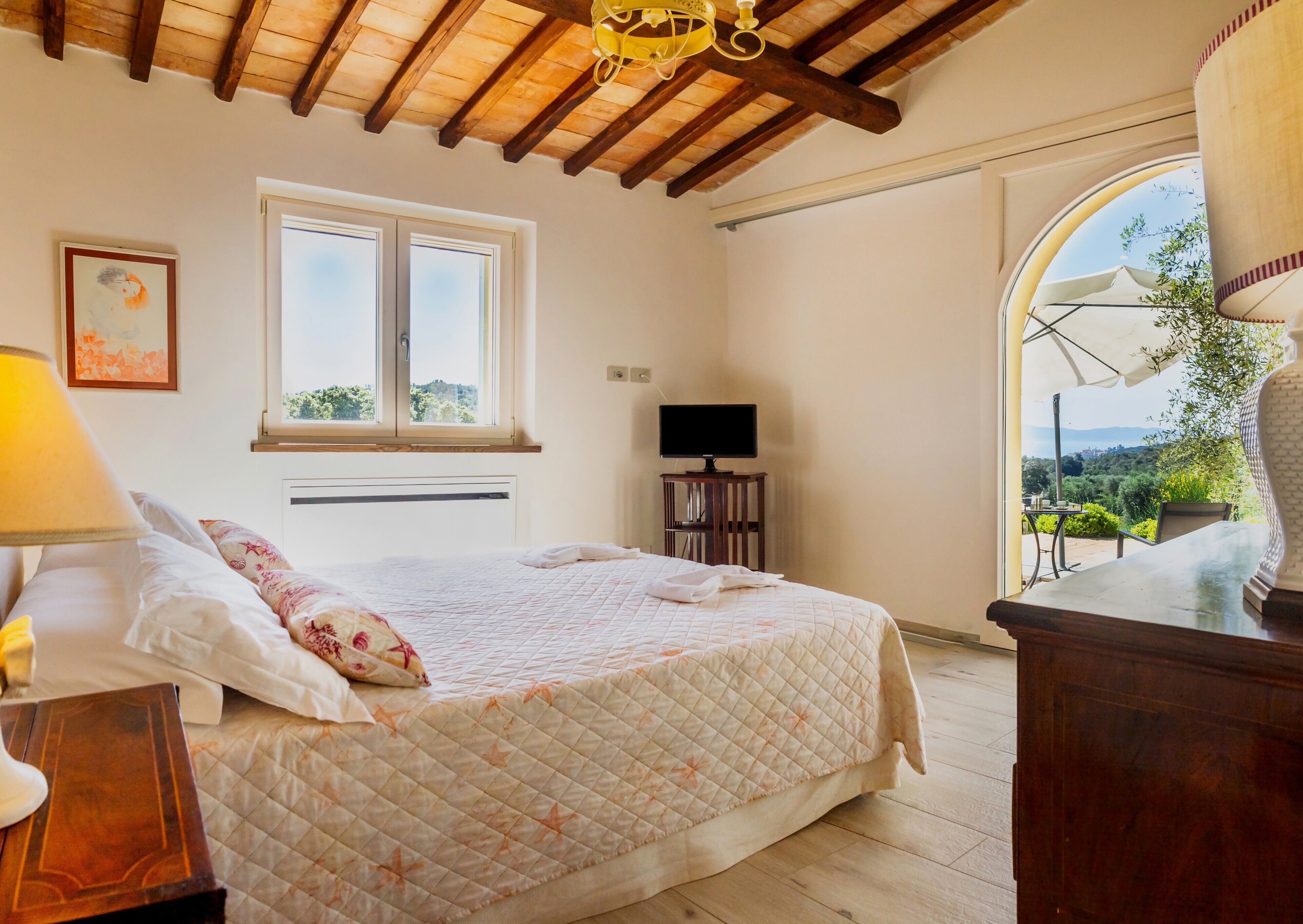 A bedroom with a bed, a TV, a window, and an outdoor view.