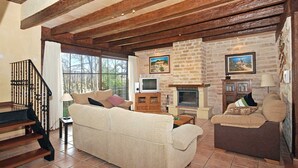 A living room with a fireplace, stone walls, and a staircase. - Villa 'Carbonell' with Mountain View, Wi-Fi and Air Conditioning (Alcudia)