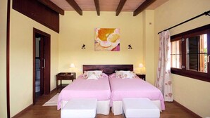 A double room with two beds, a wooden ceiling, a painting, and a window with curtains. - Villa 'Carbonell' with Mountain View, Wi-Fi and Air Conditioning (Alcudia)