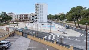 A modern building with a central courtyard, a parking area, and a street with cars and a pedestrian crossing. - Apartment 'Mar de Laura' with Shared Pool, Private Terrace, and Shared Garden (Miami Playa)