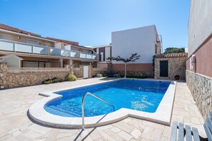 Une piscine bordée de pierres, avec un escalier en métal et un mur en pierre.