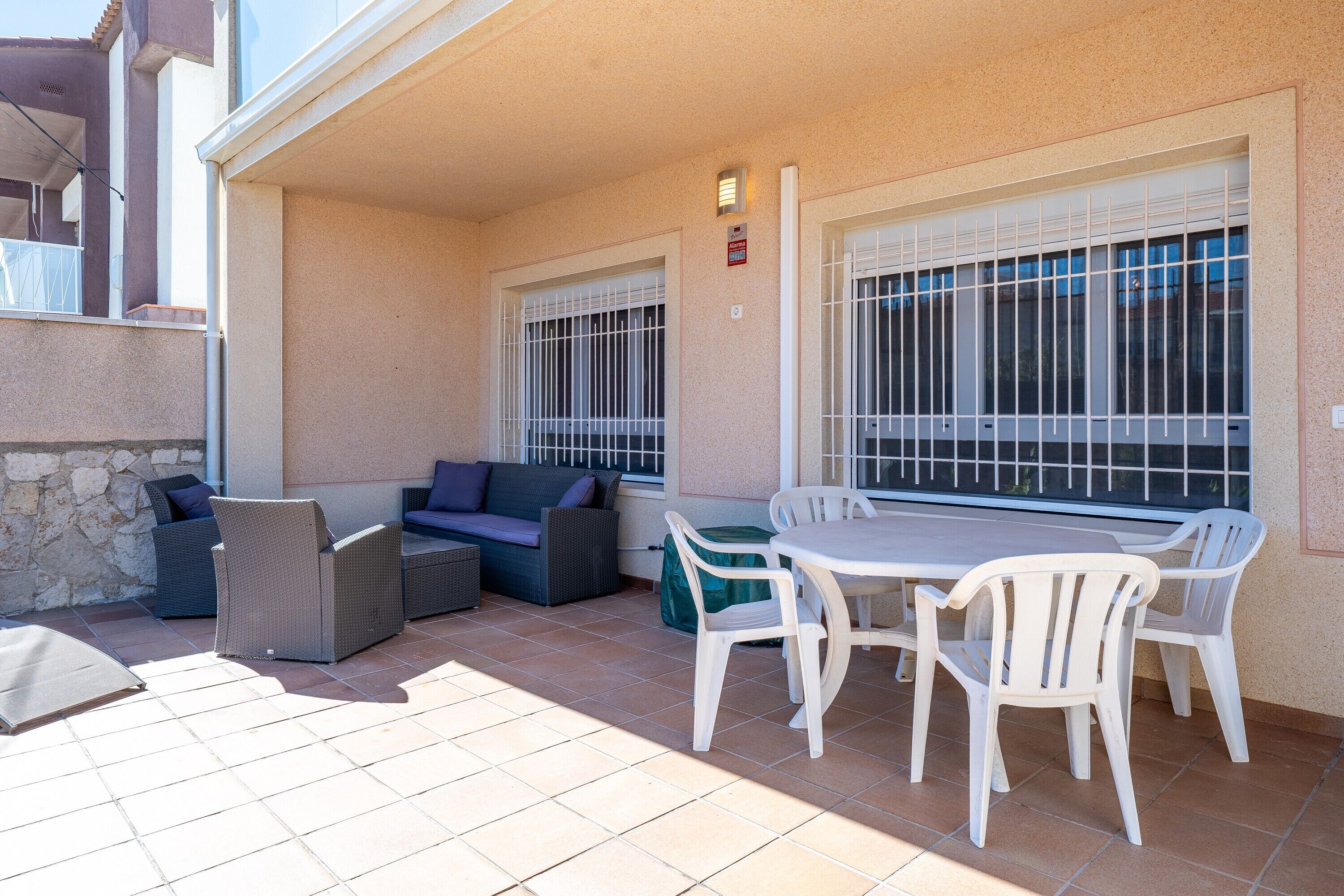 Une terrasse extérieure couverte, avec une table et des chaises, un canapé et un mur en pierre.