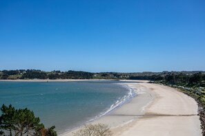 A beach with a clear sky, sandy shore, and a distant tree line. - Charming Villa 'L'hermine' with Sea View, Private Terrace & Wi-Fi (Locquirec)