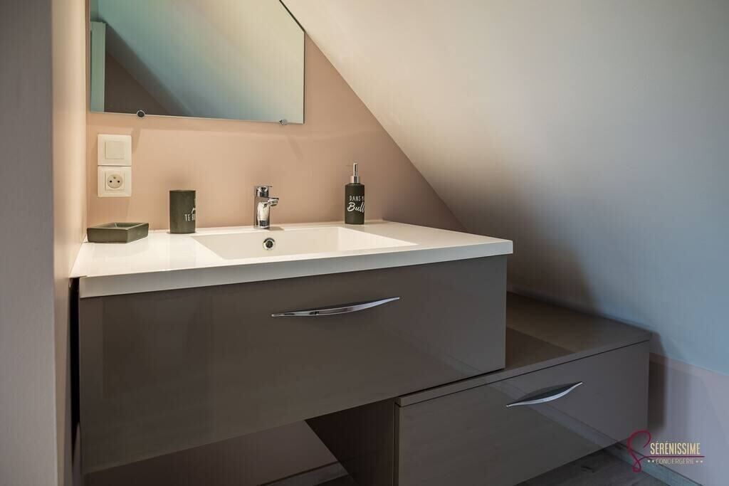 A modern bathroom with a white vanity, a mirror, and a towel rack.
