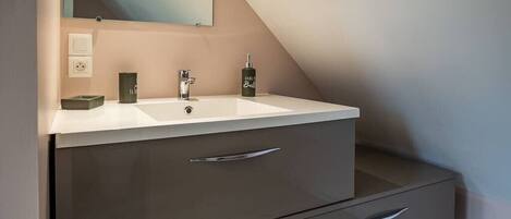 A modern bathroom with a white vanity, a mirror, and a towel rack.