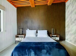 A modern bedroom with a wooden ceiling, a large bed with white linens, two bedside tables, and a marble wall.