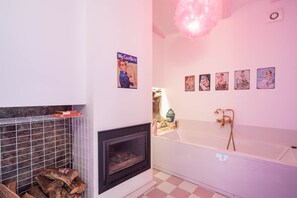 A bathroom with a bathtub, a fireplace, and wall art.
