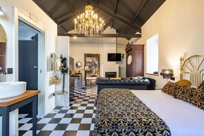 A bedroom with a checkered floor, a large bed, a chandelier, a TV, and a wardrobe.