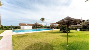 A swimming pool with a clear blue water, surrounded by grass and palm trees. - Studio Apartment 'Butiplaya Frontline Beach' with Sea View, Wi-Fi and Air Conditioning (La cala de Mijas)