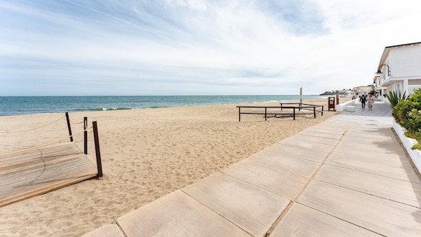 A beach with a wooden deck, a concrete walkway, and buildings in the background. - Studio Apartment 'Butiplaya Frontline Beach' with Sea View, Wi-Fi and Air Conditioning (La cala de Mijas)