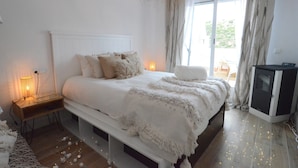 Un dormitorio con cama, lámparas de noche, televisor y vistas al exterior.