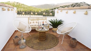 Una terraza con mobiliario de mimbre, una mesa redonda y vistas a las colinas.