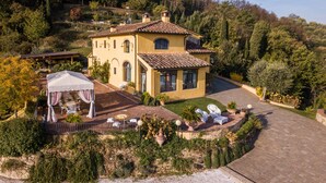 Une grande maison avec un toit en tuiles, un patio couvert et un jardin.