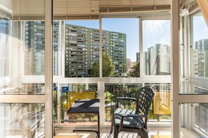 A balcony with a table and chairs, large windows, and a view of high-rise buildings. - Apartment 'Nuevo Acapulco' with Mountain View, Shared Pool and Shared Garden (Fuengirola)